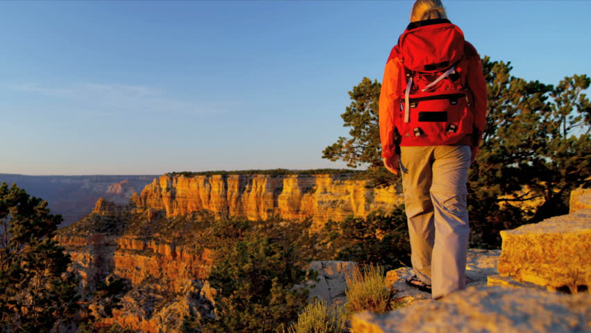 Lone female hiker watching the sun setting over the canyons, USA, Shot on Red Epic