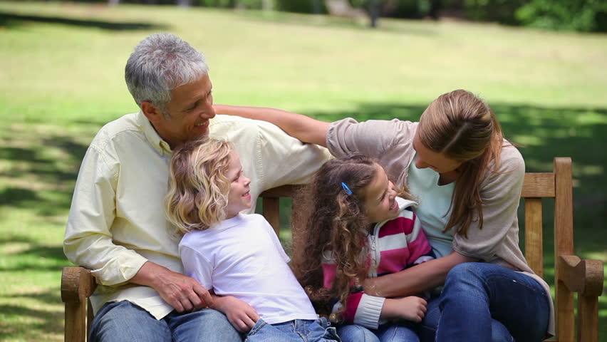 Family posing together on a bench in a park