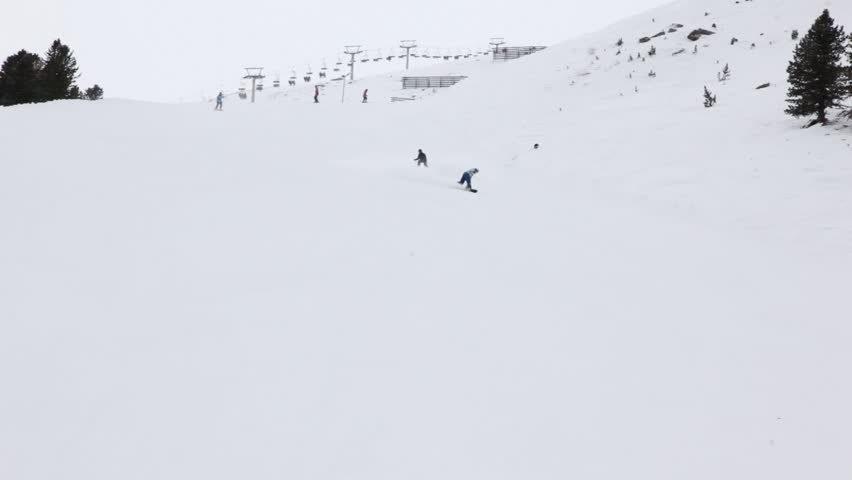 Skier and snowboarder go on mountain slope downwards mountain