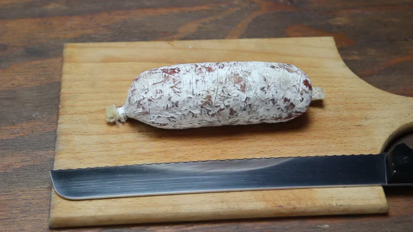  salami and  knife on wooden cutting board