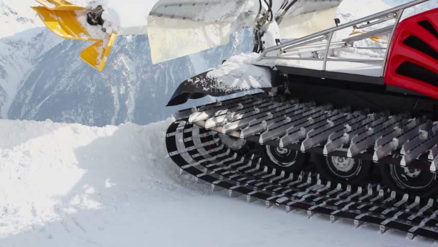 Machine for skiing slope preparations in Austrian Alps at background of mountains