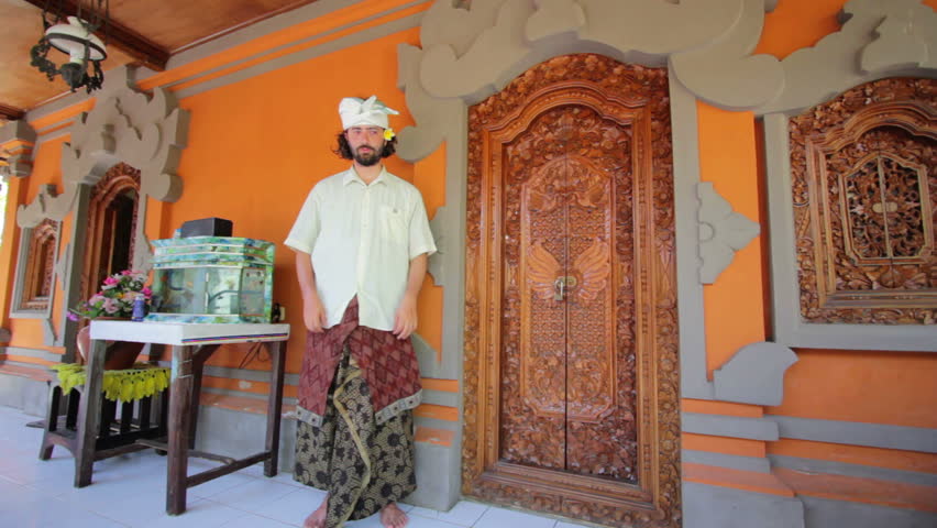 Caucasian man in Balinese clothes saluting Asian style both hands