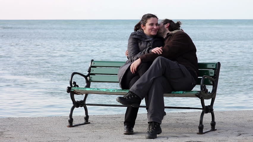 lovers kissing on a park bench