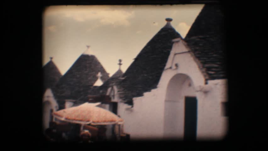 Vintage 8mm. Typical cone shaped houses (trullo) and tourists in Alberobello, a unique Italian town
