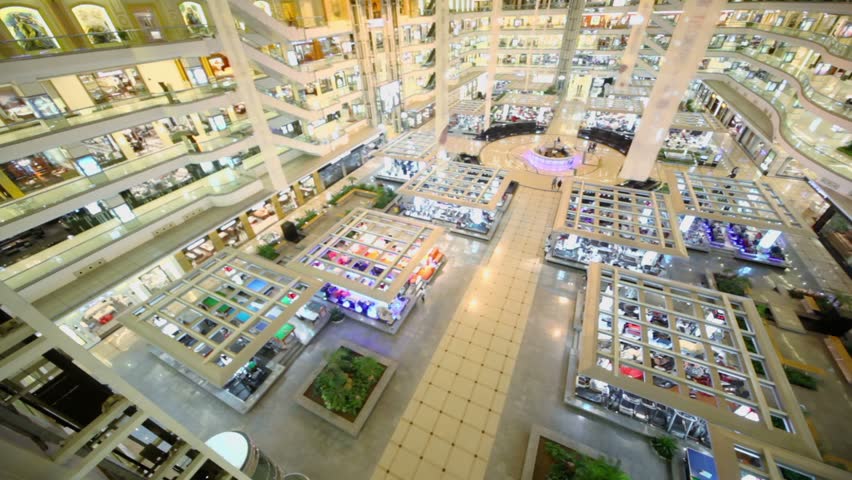 People walk around in multilevel shopping center with several elevators, view from above