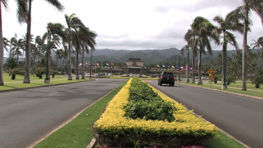Entrance to BYU University Hawaii. Brigham Young University. Tropical lines road leads into campus. Flowers and palm trees.