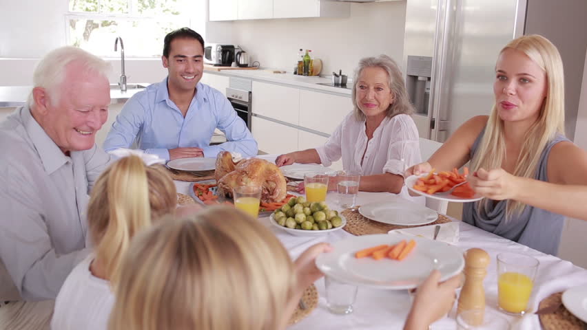 Happy mother serving carrots to son at family dinner in kitchen