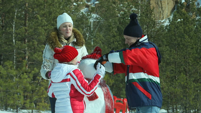 Lovely family with positive attitude making a snowman with a carrot nose