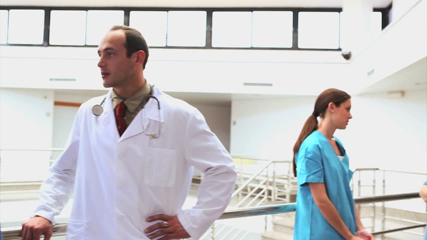 Doctor holding a clipboard next to nurses in hospital hallway