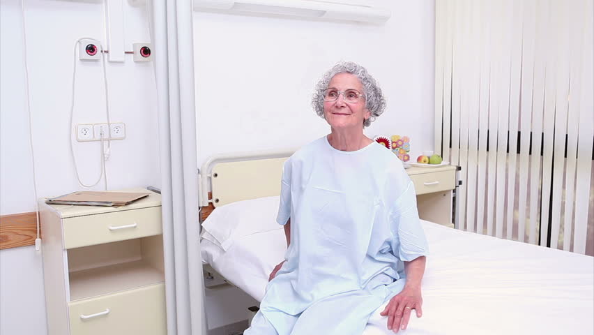 Nurse assisting an elderly patient in hospital ward