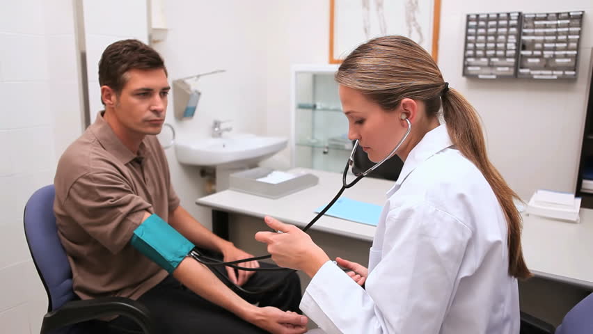 Smiling doctor measuring the blood pressure of his patient in an examination room