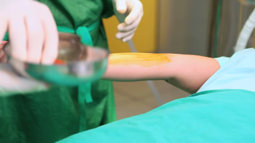 Video of a surgeon disinfecting the forearm of a patient with a compress in an operating theatre