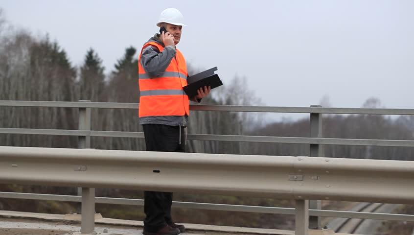 Engineer with a cell phone and a folder on the bridge