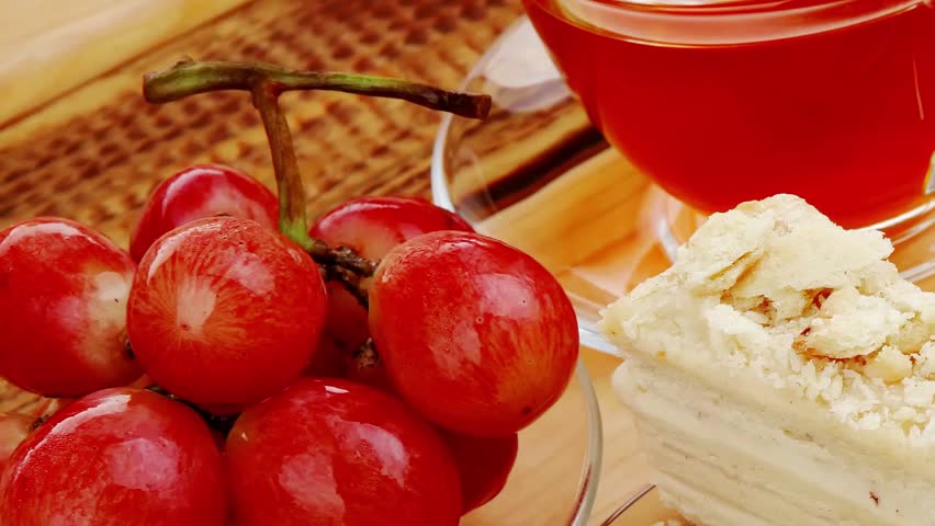 grapes with tea and cake on wooden table