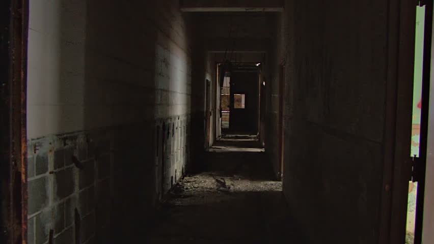 A dark hallway of nasty ruin and decay in a wretched, decrepit abandoned building. Glidecam shot.