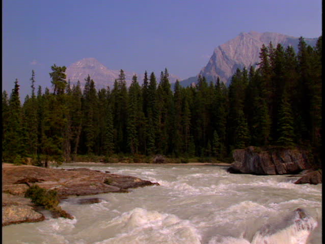 Tilt down from wide shot and zoom into the turbulent of Kicking Horse River in the Canadian Rockies