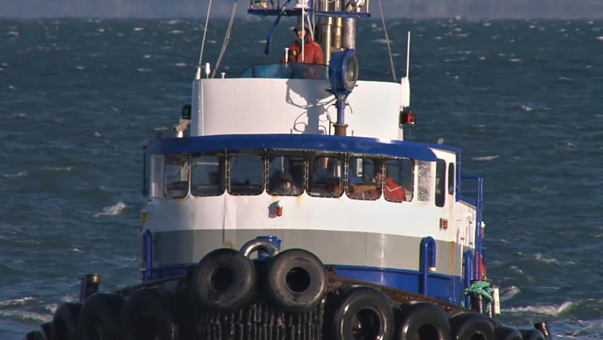 HOMER HARBOR, AK - CIRCA 2012: Working tug boat Redoubt returning to harbor.  Close tracking shot, follows, then reverse zoom as boat enters no wake zone, allowing boat to pass out of frame