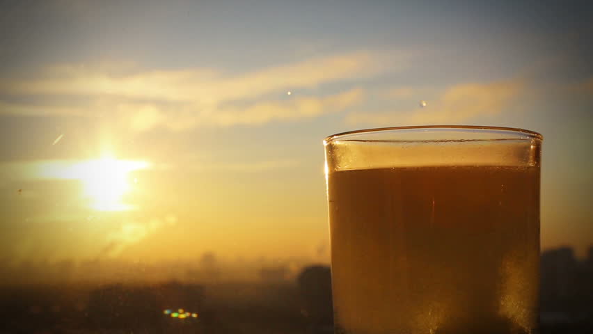 pill falling in a glass on a background of defocused city and sun, conceptual footage