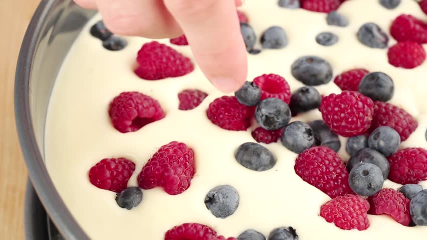 Fresh berries being sprinkled on a fridge cake
