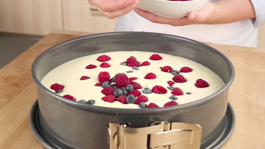 Fresh berries being sprinkled on a fridge cake