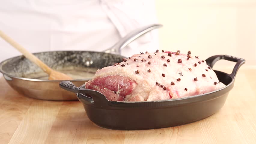 A studded pork loin joint being brushed with a honey-beer glaze