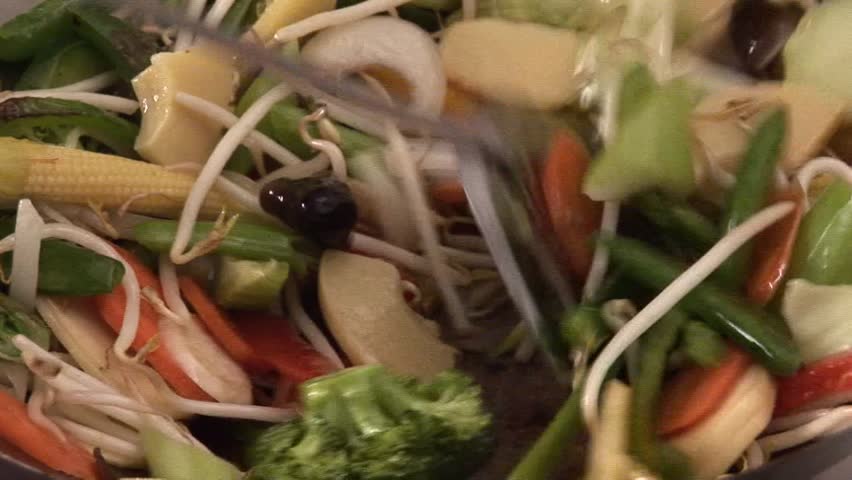 Mixing sprouts with vegetables in a wok