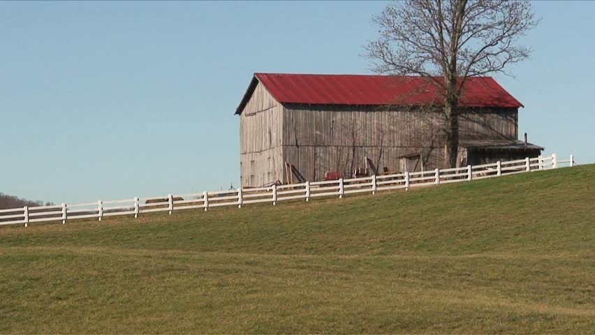 Pan of a farm field and barn in Tennessee.