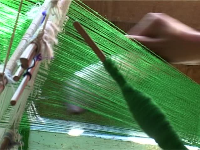 Woman on the hand loom is weaving green fabrics. Inle lake in Burma.