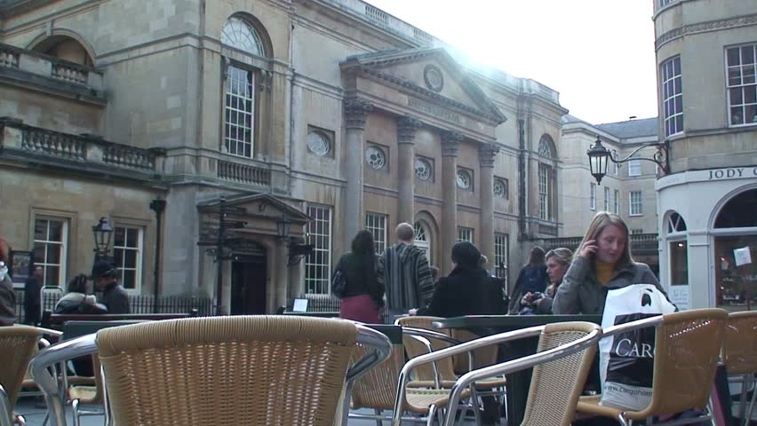 BATH, SOMERSET, UNITED KINGDOM - CIRCA 2011: Woman sits at cafe tables across from the Roman Baths in Bath, Somerset.
