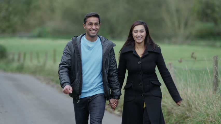 An attractive couple holding hands and enjoying a walk down a country lane. Slow motion