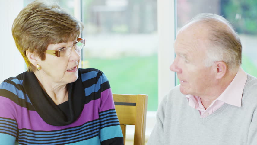 A mature married couple are sitting together at a table and working out their household accounts