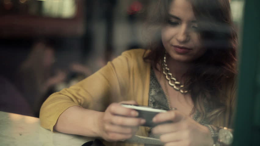Young woman using smartphone in cafe, steadicam shot
