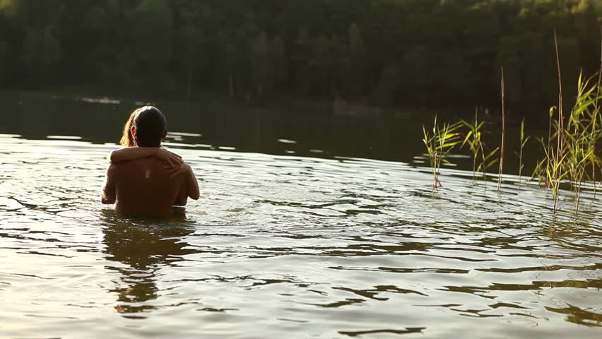Young couple embracing and kissing in romantic attitude into the water in lonely romantic lake