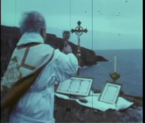 Rear view of priest holding up chalice during outdoor ritual