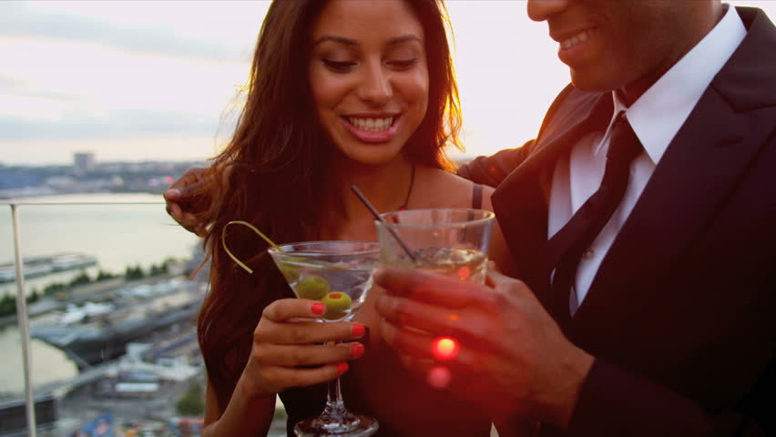 Young happy multi ethnic woman and man dating at luxury cocktail party dressed in black sun lens flare shot on RED EPIC