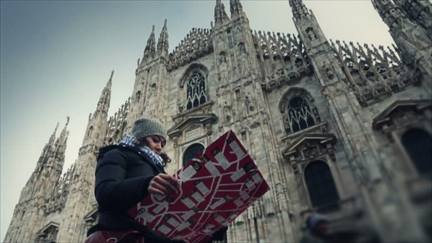 Tourist in front of the facade of the duomo of Milan looking the map 