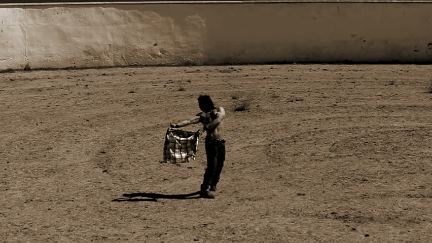 Man training as bullfighter in empty arena in a sunny day