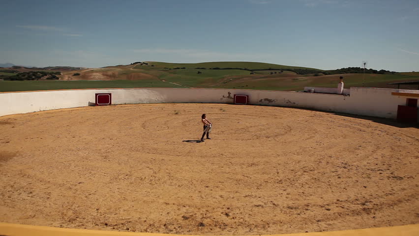 Man training as bullfighter in empty arena in a sunny day
