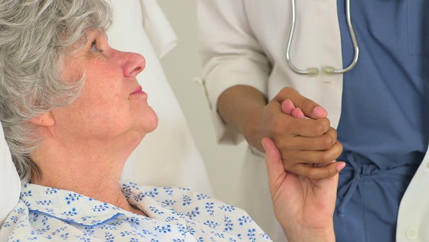 Caucasian patient holding her doctor's hand