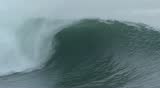 Close-up of a large, stormy ocean wave breaking in slow motion off of the coast of central California.