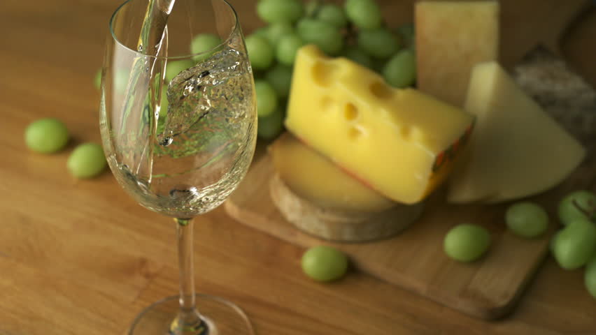 Pouring white wine into glass with grape and cheese shooting with a high speed camera.