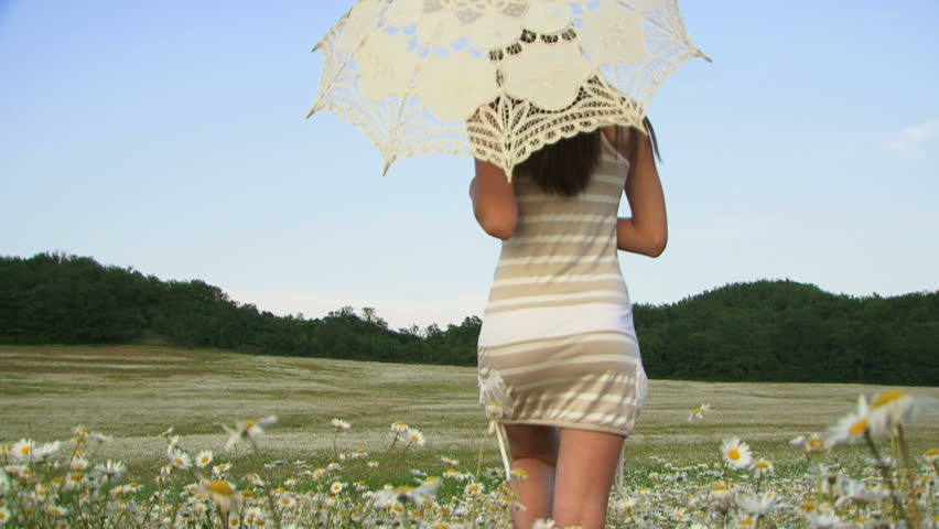 Woman walking across the field with a sun umbrella.
Woman with umbrella.