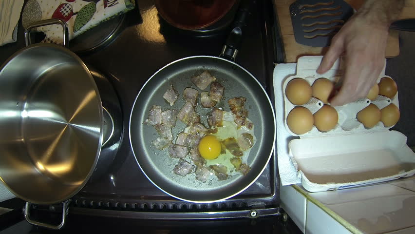 Sunny Side Up Eggs With Bacon.
Hands cracking eggs into a frying pan. HD1080p.