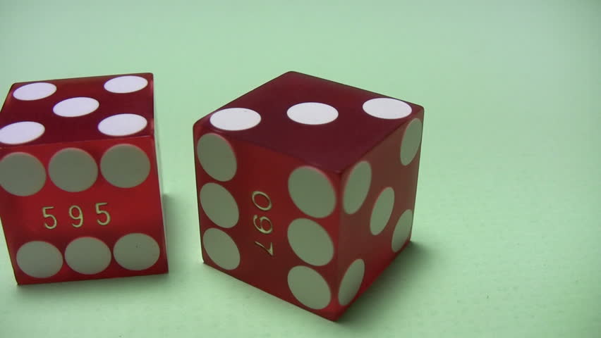 Rotation of two red craps dice on green background with light shadows