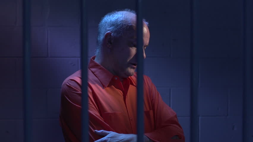 Man behind bars sitting in his jail cell