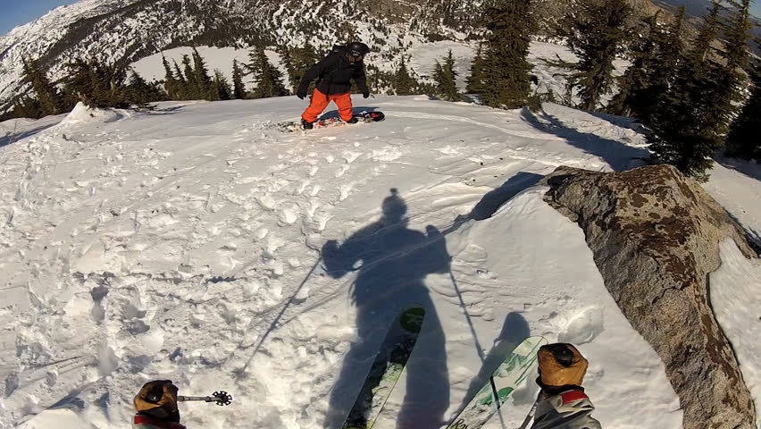 A skier carves back and forth as he rides down a mountain covered in fresh powder during the day. It is shot with a camera mounted to the athletes head and provides a POV, point of view, perspective.