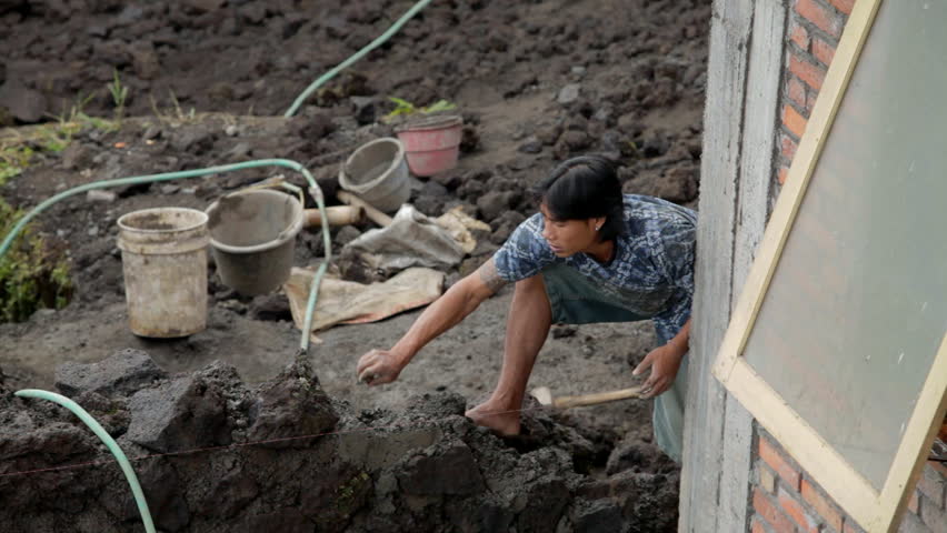 BALI - FEBRUARY 25: Men building a wall out of volcano rock on February 25, 2012 in Bali, Indonesia. Volcano rock and dirt is the main source of material in the mountains of Bali. 