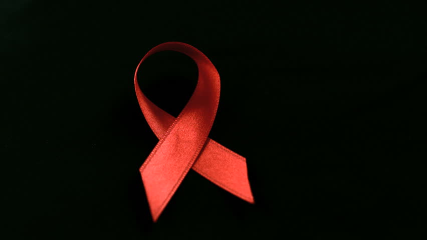 Condom dropping down beside red ribbon in slow motion