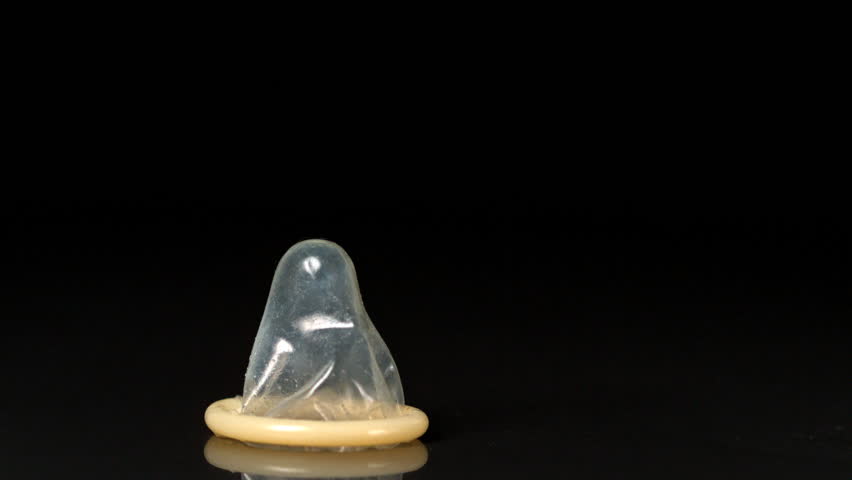 Condom falling over on black background in slow motion