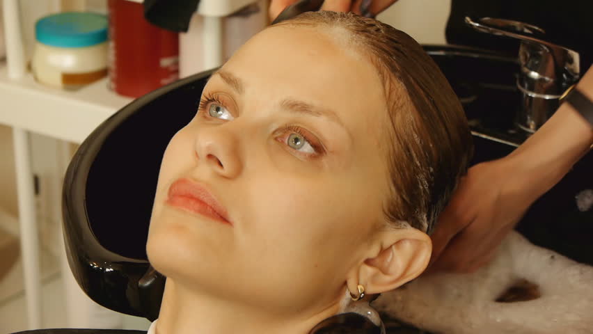 Beautiful young woman getting a hair washed at a hair salon.  